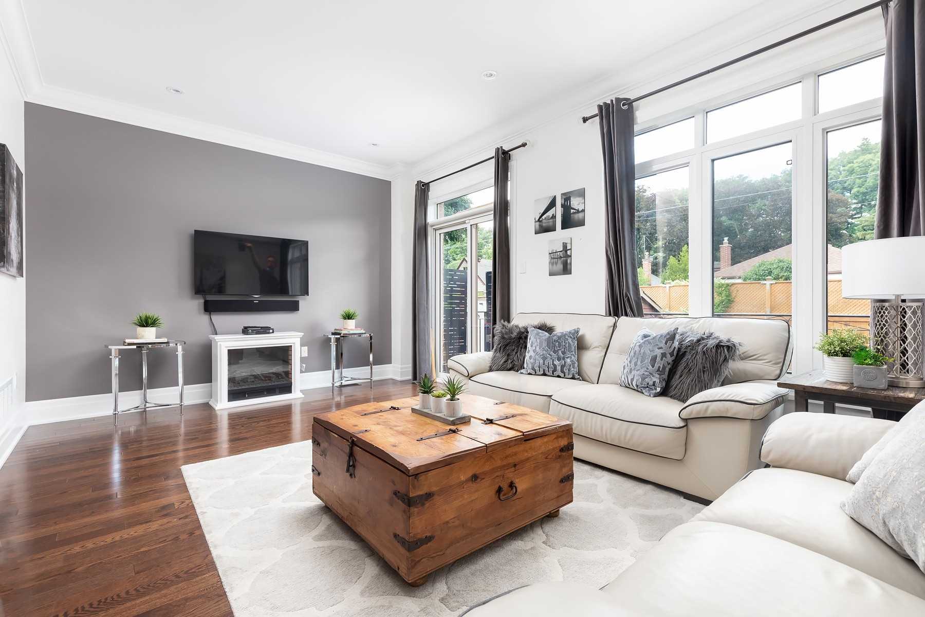 Family room with a grey accent wall, fireplace, wall-mounted TV, and windows overlooking the backyard