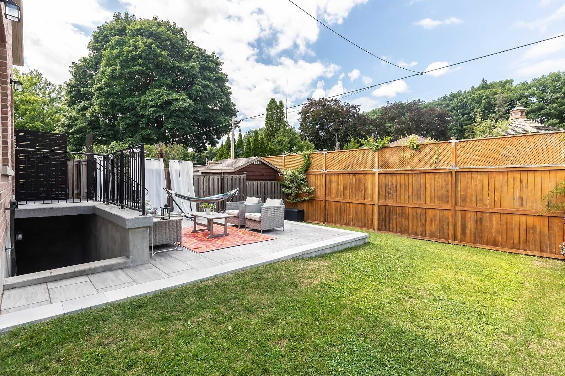 Professionally landscaped backyard at 106A Hollis Avenue with a stone patio, outdoor furniture, and a hammock