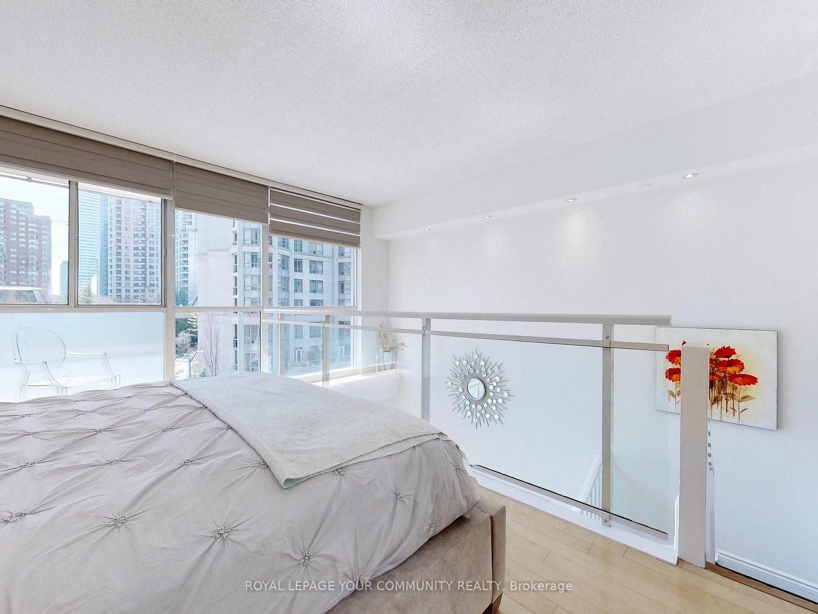 Primary bedroom on the upper loft level with floor-to-ceiling windows, city views and the glass railing