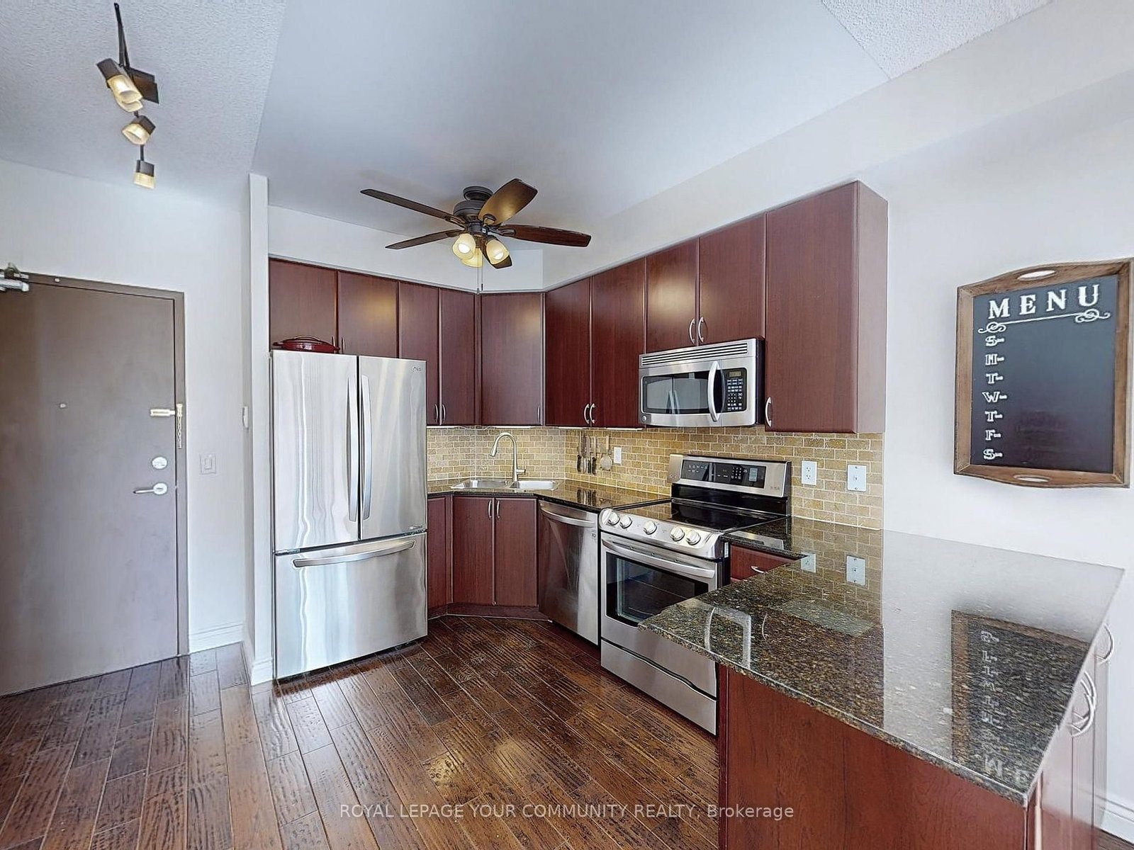 Kitchen of the loft with dark wood cabinetry, stainless steel appliances and granite counters