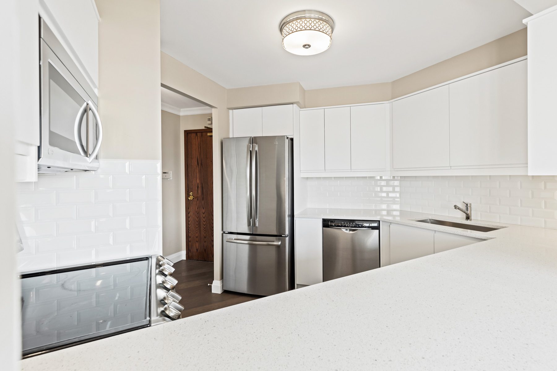 Refreshed kitchen of Suite 404 with white cabinetry, stainless steel appliances and subway tile