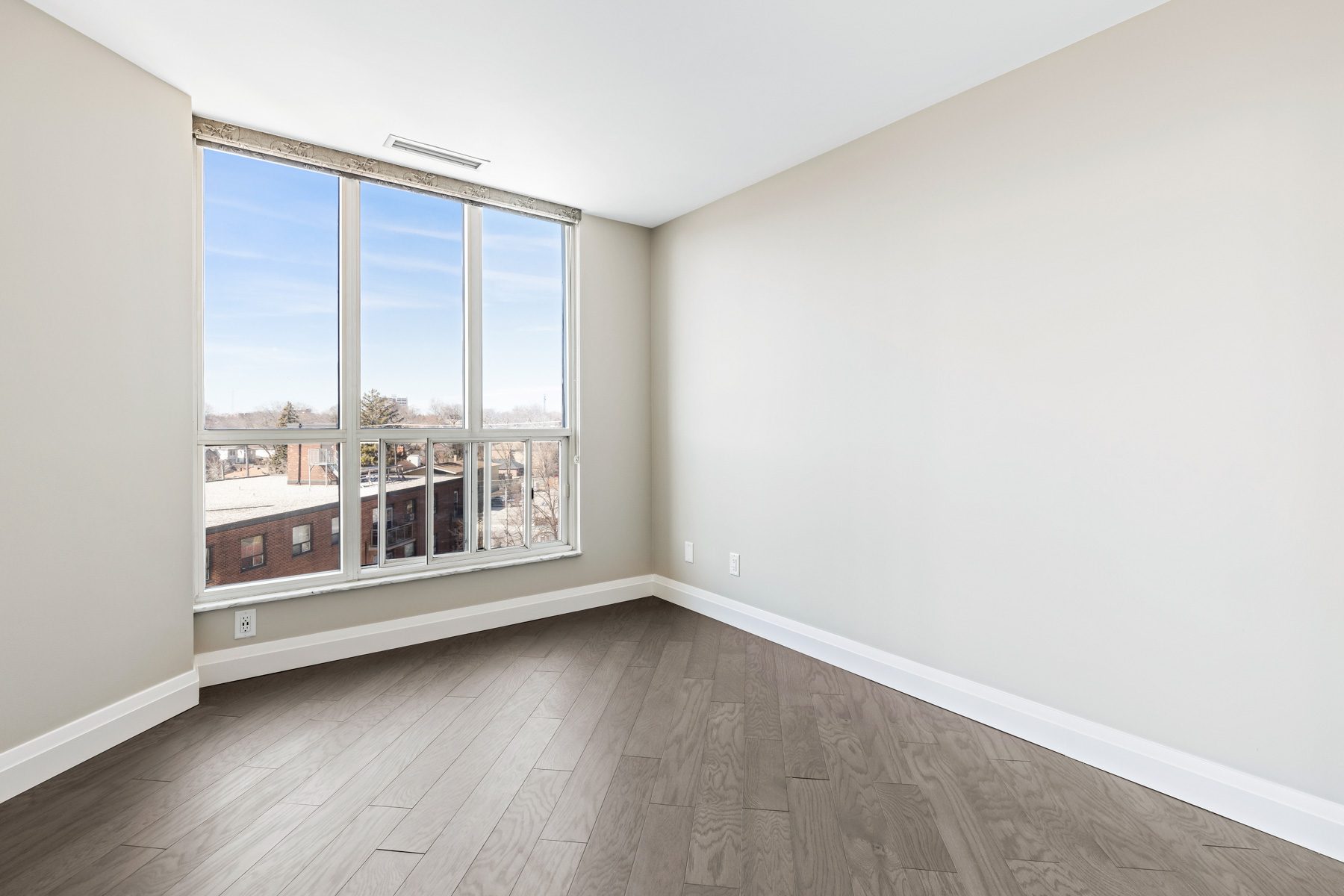 Bedroom of Suite 404 with large windows and new flooring