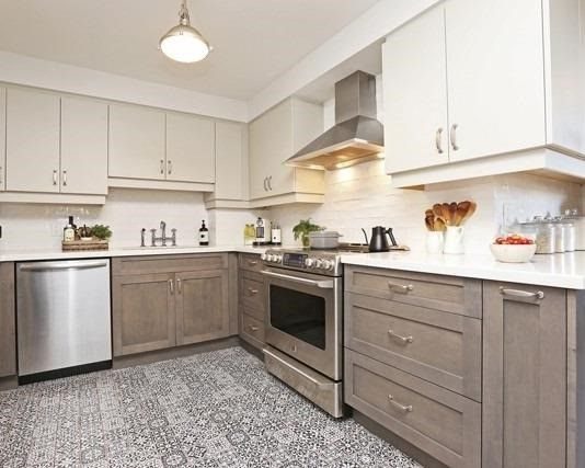 Updated kitchen with white upper cabinets, wood-tone lower cabinets, and stainless steel appliances