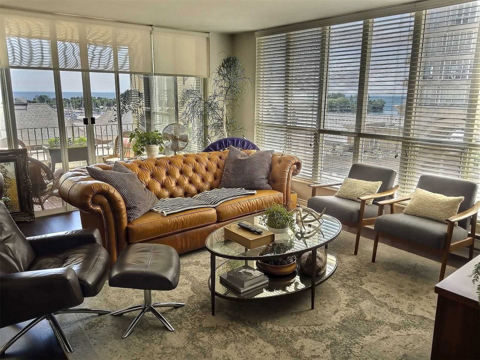 Living room with leather Chesterfield sofa and floor-to-ceiling windows framing Lake Ontario views