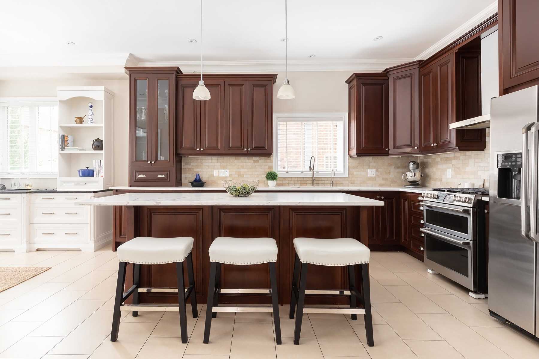 Kitchen of 33 Noce Way with cherry cabinetry, a large island with bar stools, and stainless steel appliances