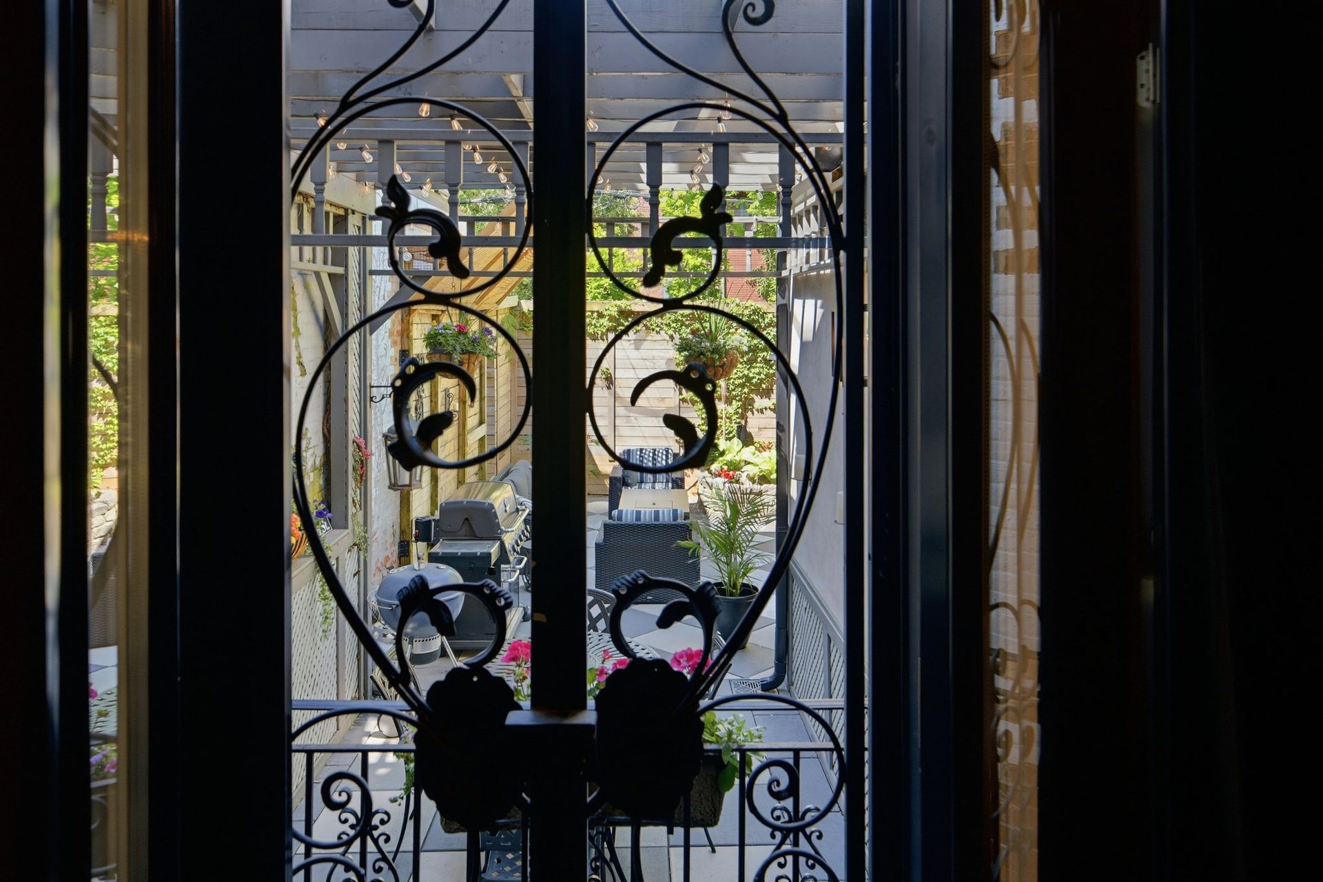Wrought-iron garden gate with scrollwork opening to the courtyard