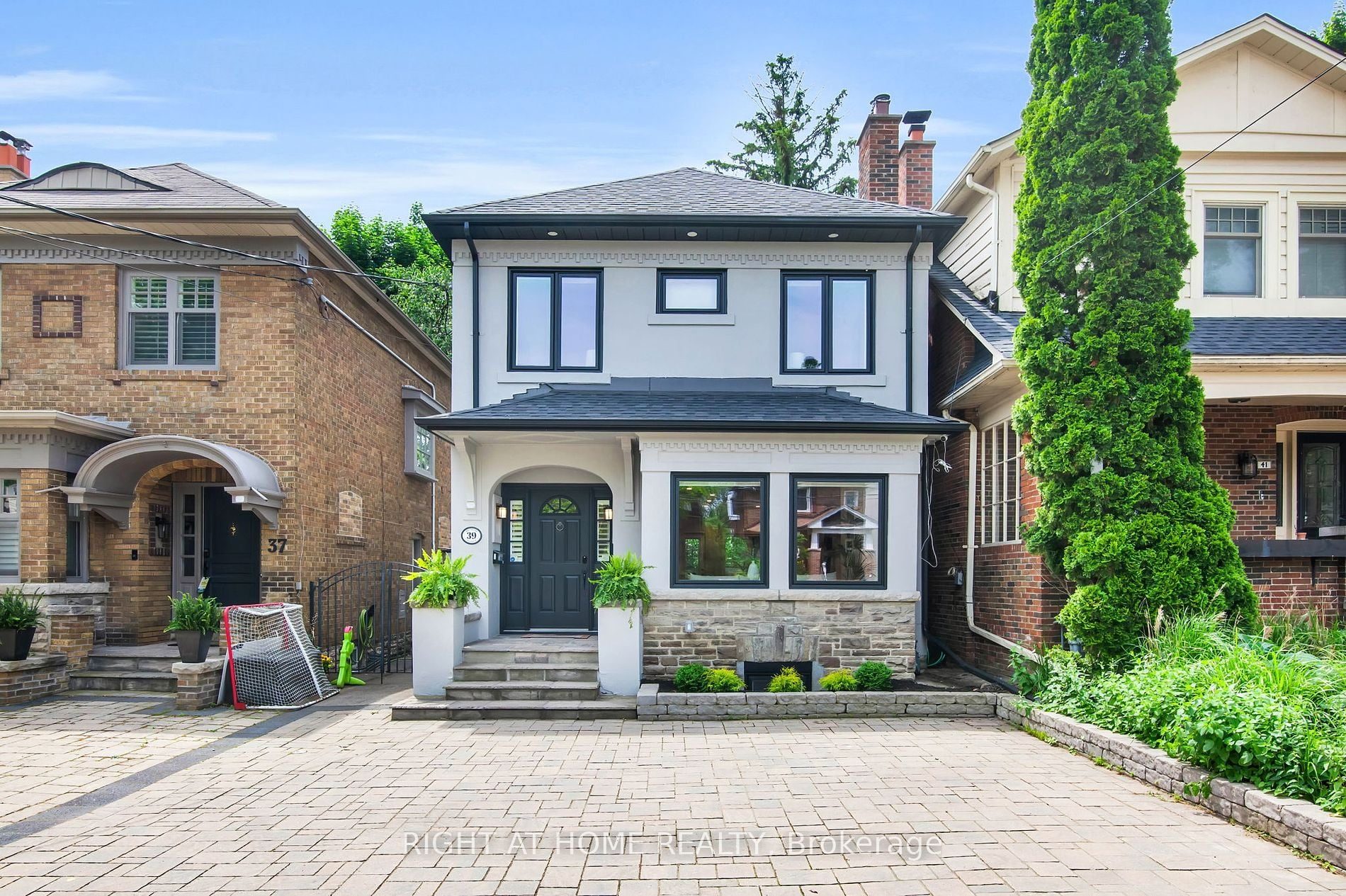 39 Melrose Avenue in Lawrence Park North, Toronto — a renovated stucco 2-storey with black-framed windows, stone base and a double interlock driveway