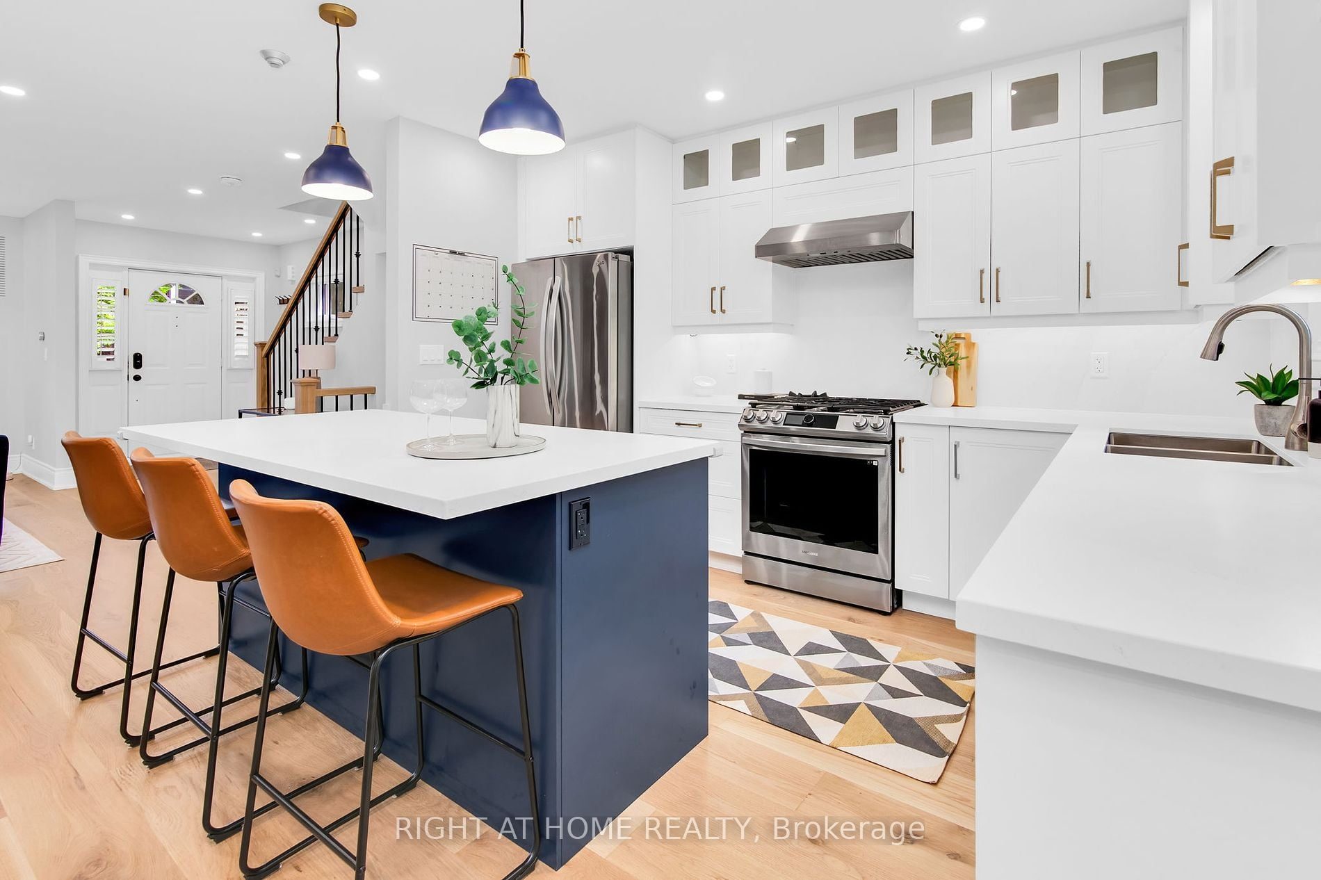 The custom kitchen at 39 Melrose Avenue — white cabinetry, navy island and stainless steel appliances