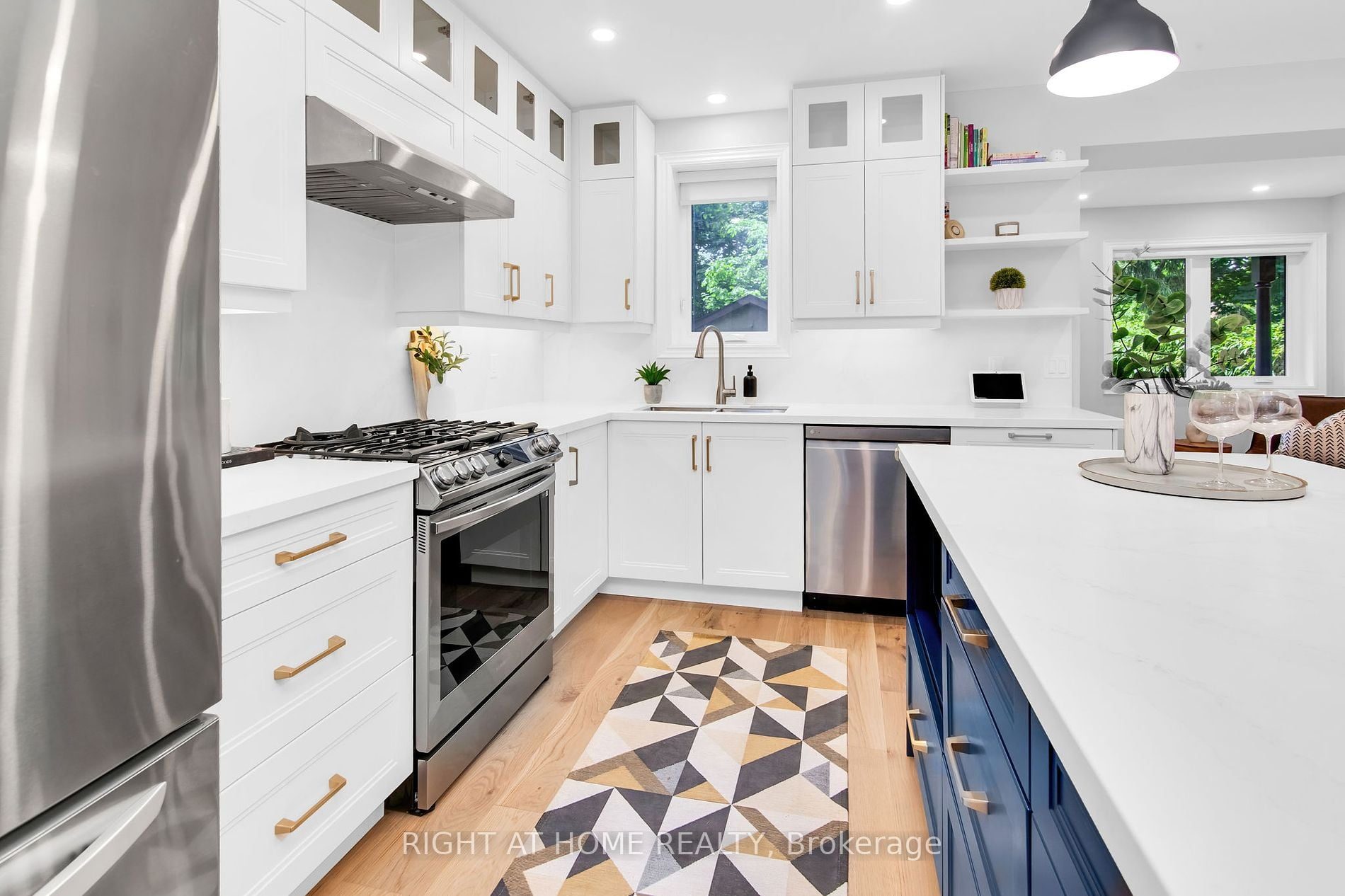 The custom kitchen at 39 Melrose Avenue — gas range work wall, quartz counters and a navy island with leather bar stools