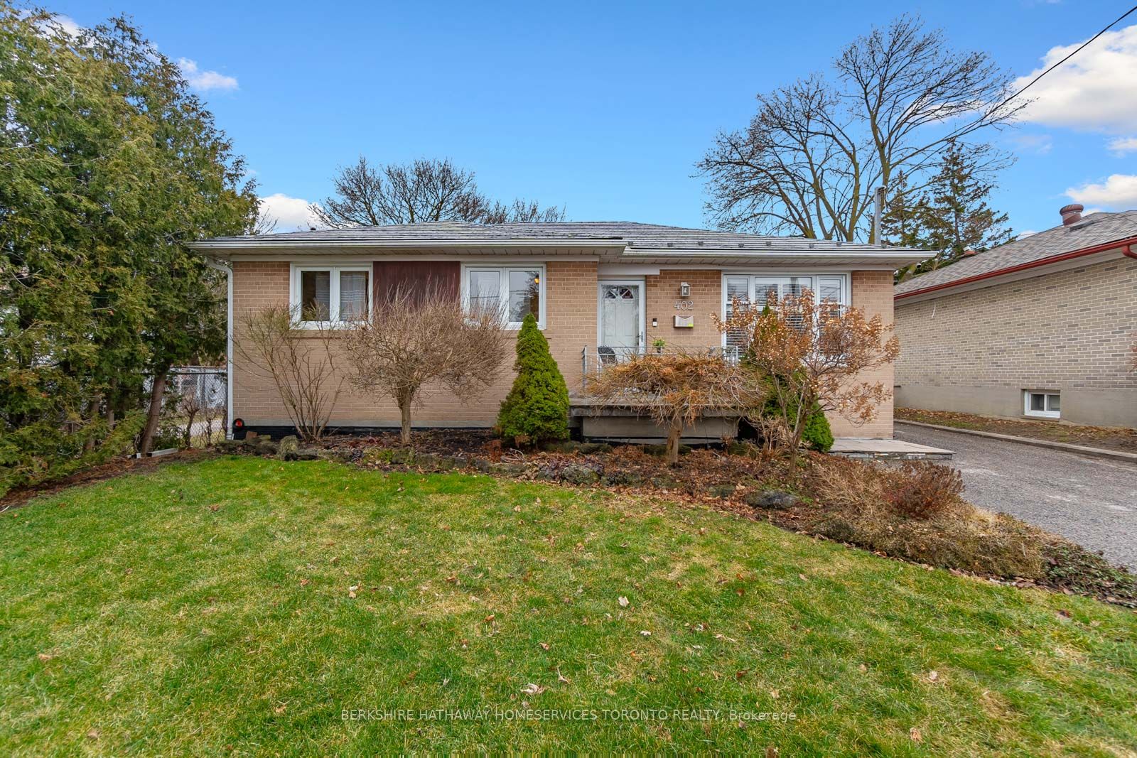 Front exterior of the brick bungalow at 402 Osiris Drive, Richmond Hill, with manicured lawn and garden beds