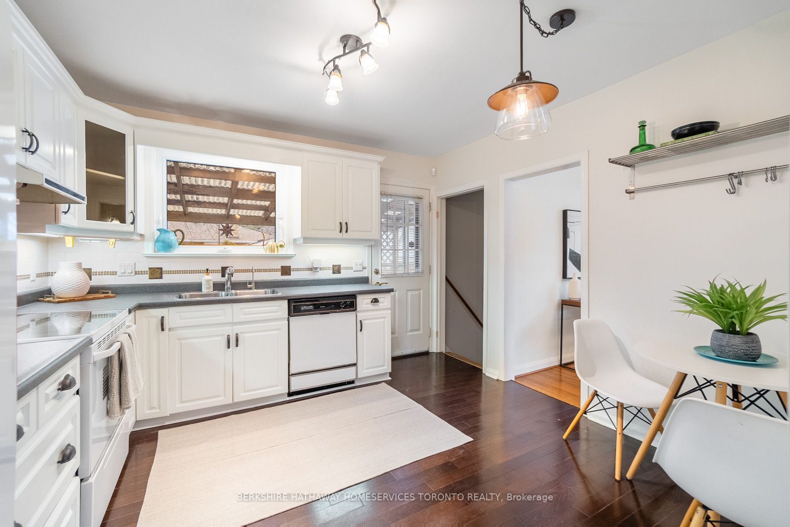 Eat-in kitchen with white cabinetry, dark countertops, and window over the sink