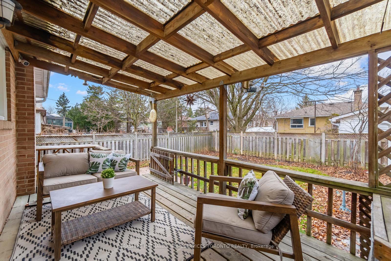 Covered rear deck with outdoor seating overlooking the fenced backyard