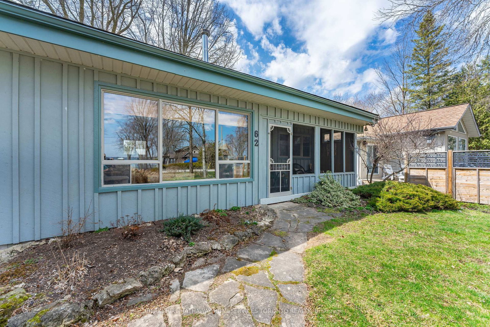 Side exterior of the bungalow showing the screened porch, large windows and flagstone path