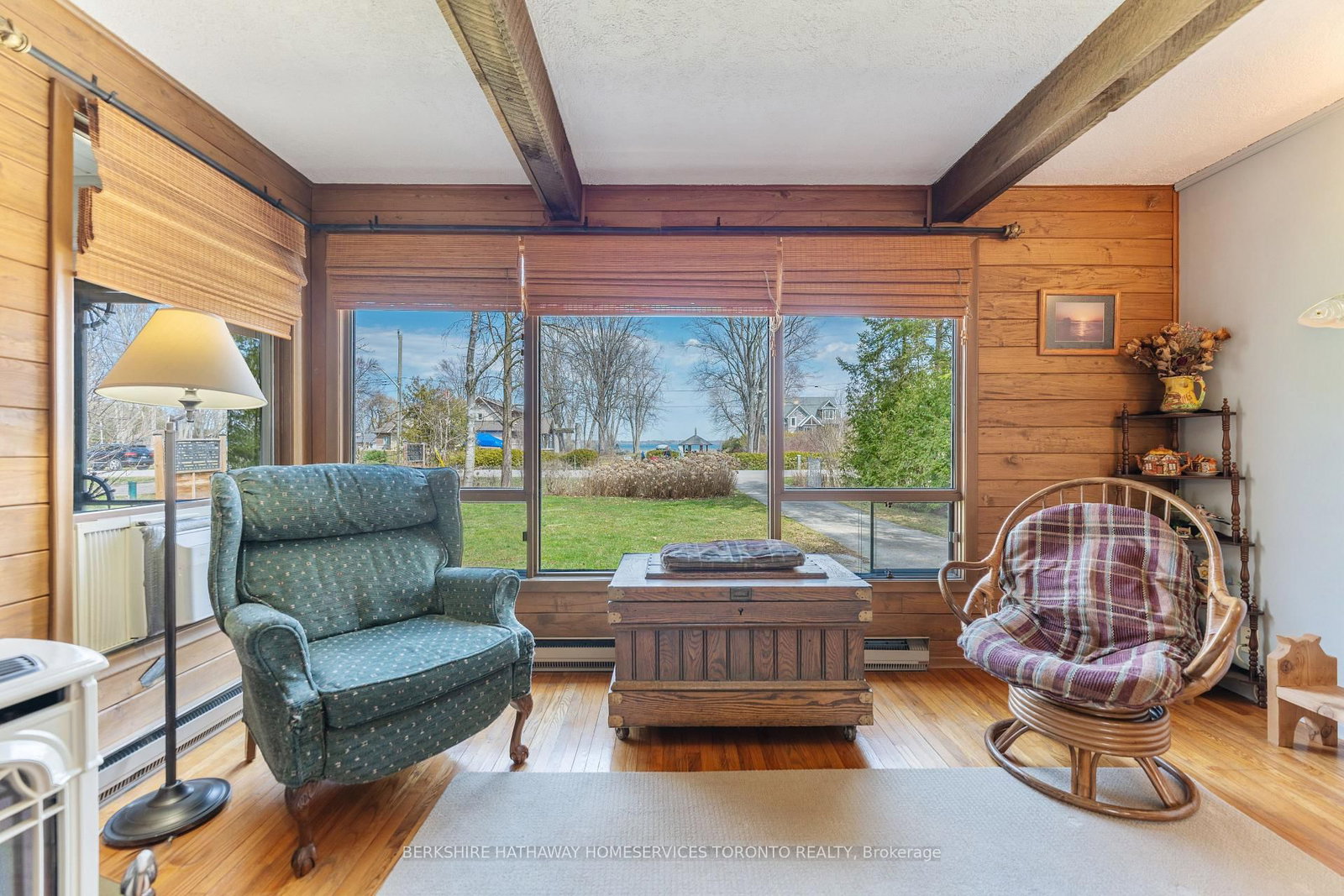 Wood-panelled living room with a wall of windows looking out toward the lake, gas stove and cottage-style seating