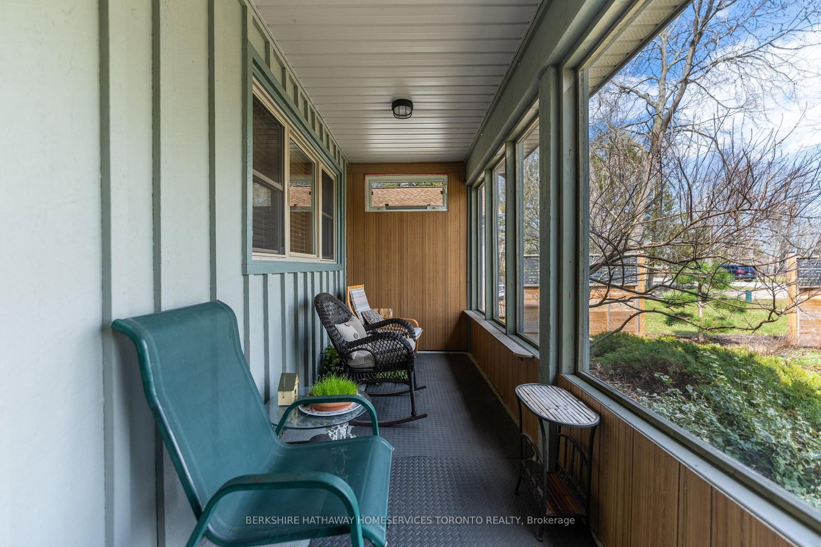 Enclosed sun porch with rocking chairs and window views over the garden