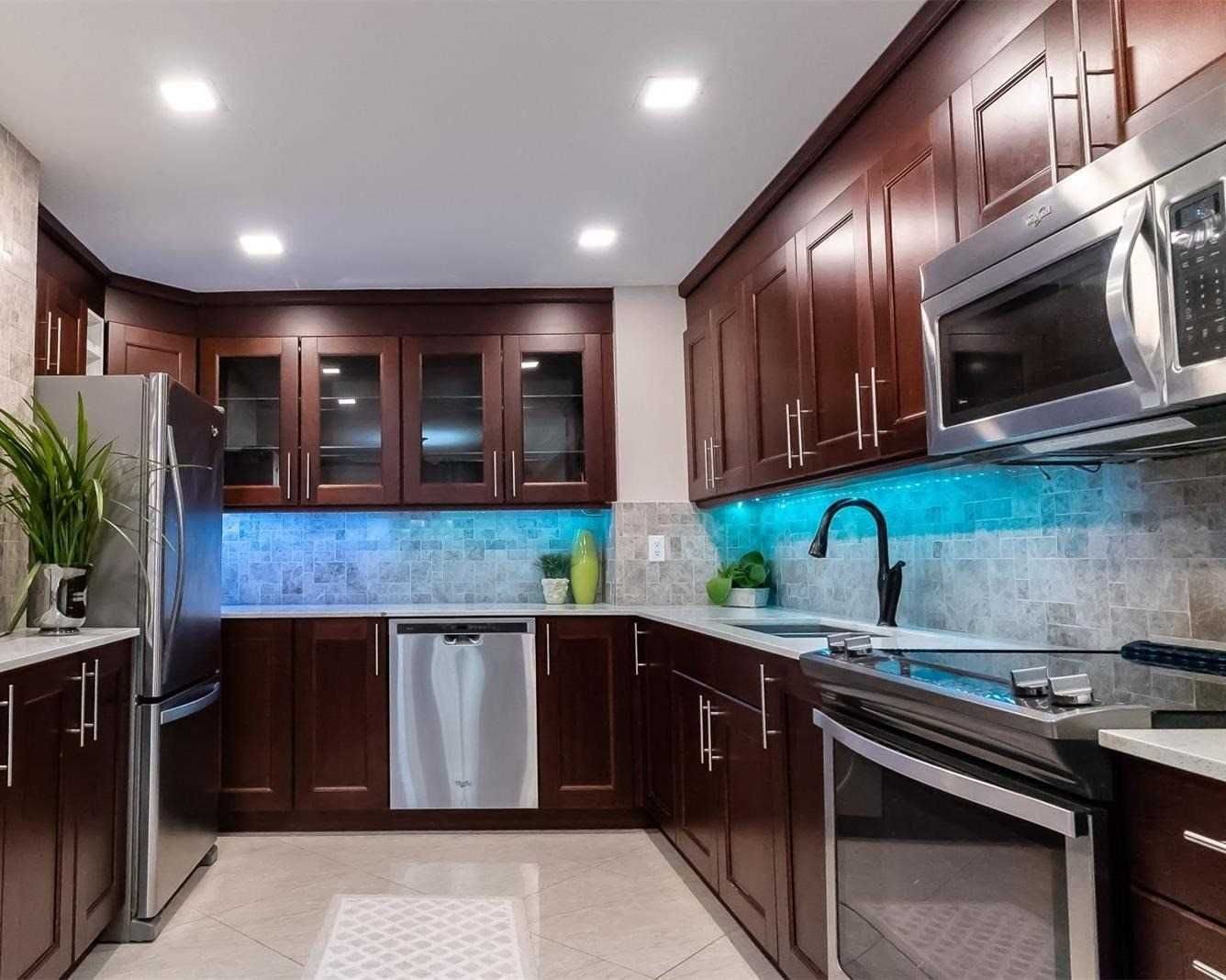 Kitchen with stainless steel fridge and dishwasher, glass-front cabinets and under-cabinet lighting