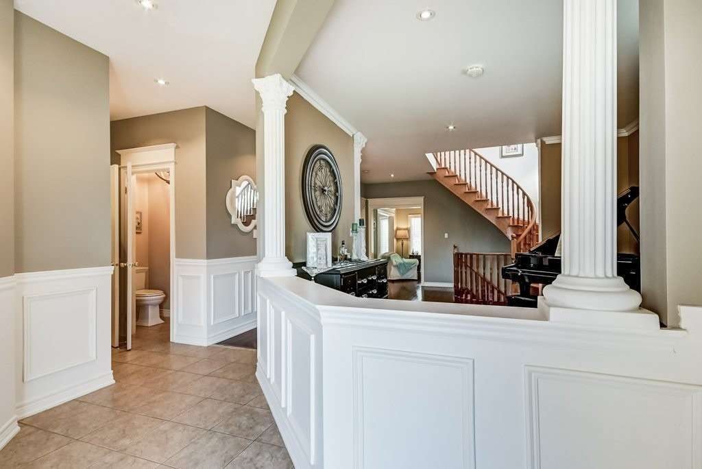 Foyer with columns, wainscoting, powder room, and curved staircase